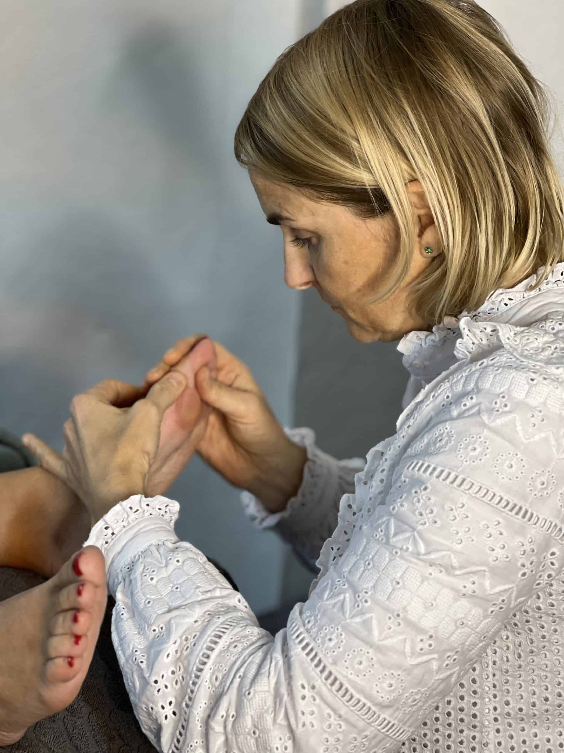 Réflexologue effectuant un massage ou une stimulation de zones réflexes des pieds.